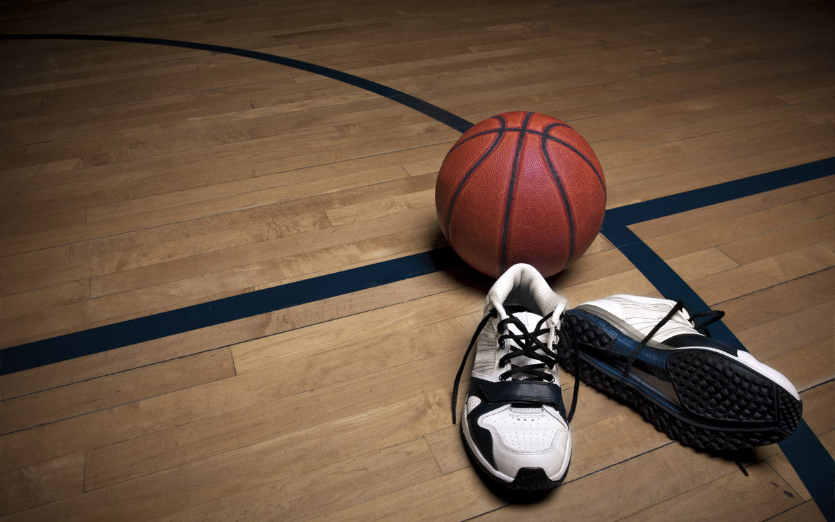 Pallone e scarpe da basket sul pavimento in parquet di una palestra