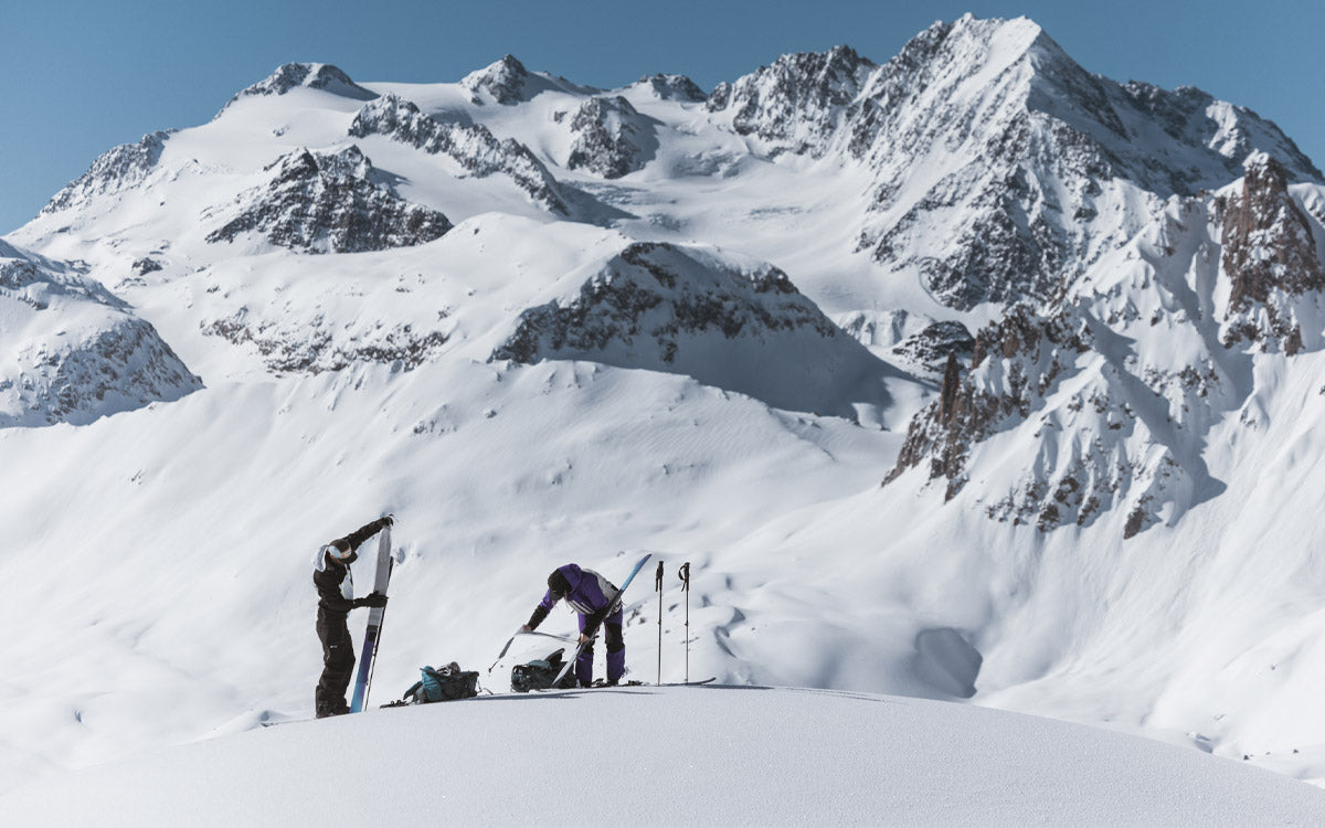 2 ragazzi, dopo aver terminato la salita, si preparano alla discesa rimuovendo le pelli dagli sci