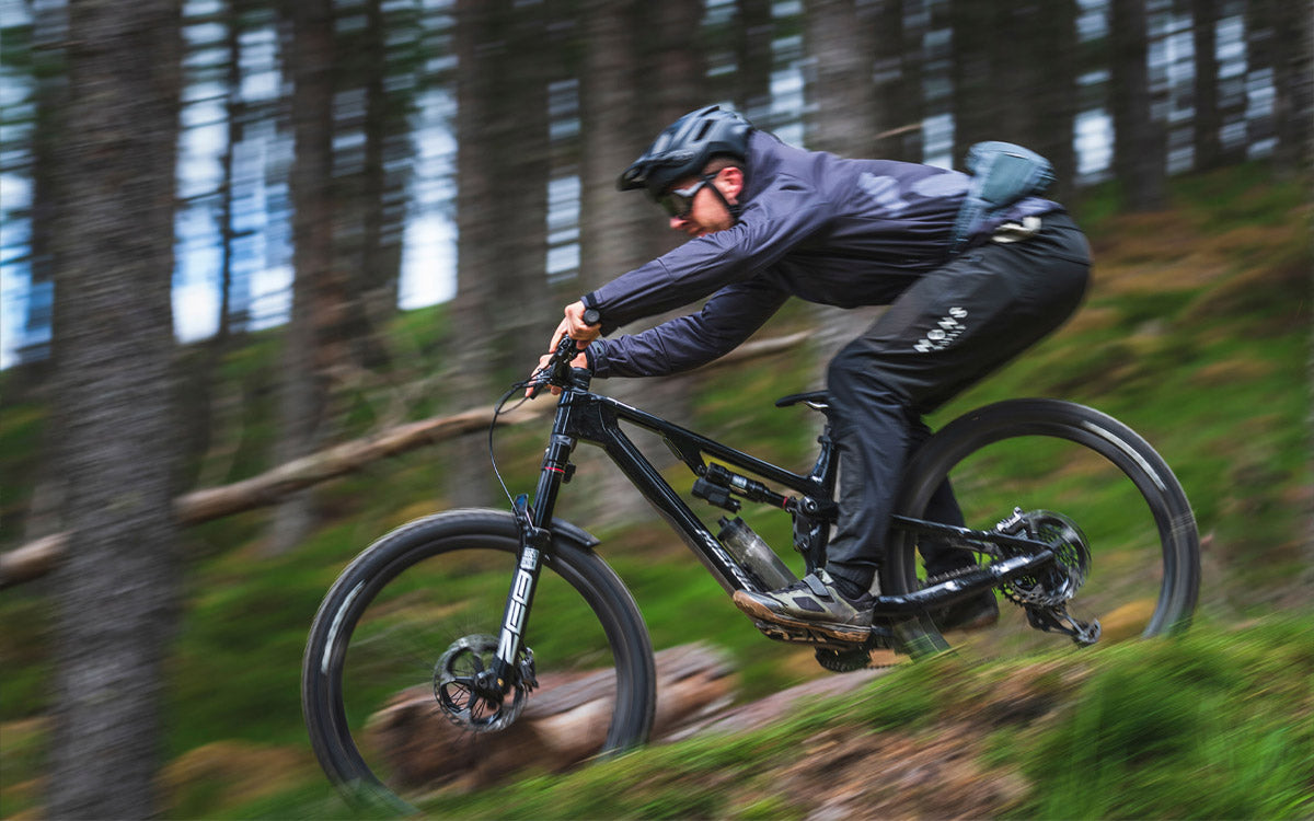 Un ragazzo mentre affronta una discesa di un percorso tecnico nel bosco, con una mtb enduro Merida