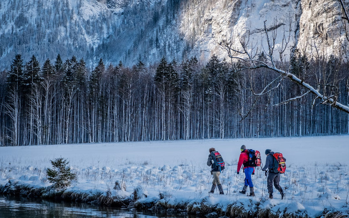 Tre persone che camminano in un paesaggio innevato