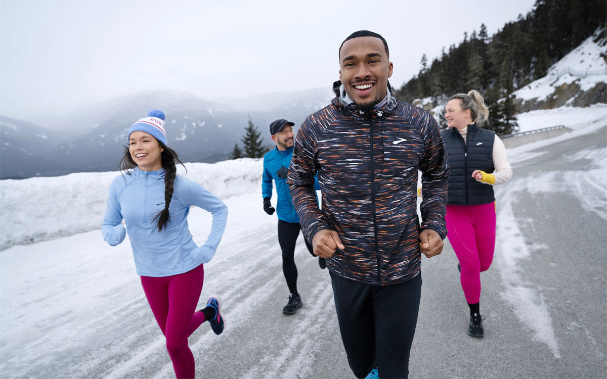 Un gruppo di ragazzi corre in un paesaggio innevato, vestono Brooks
