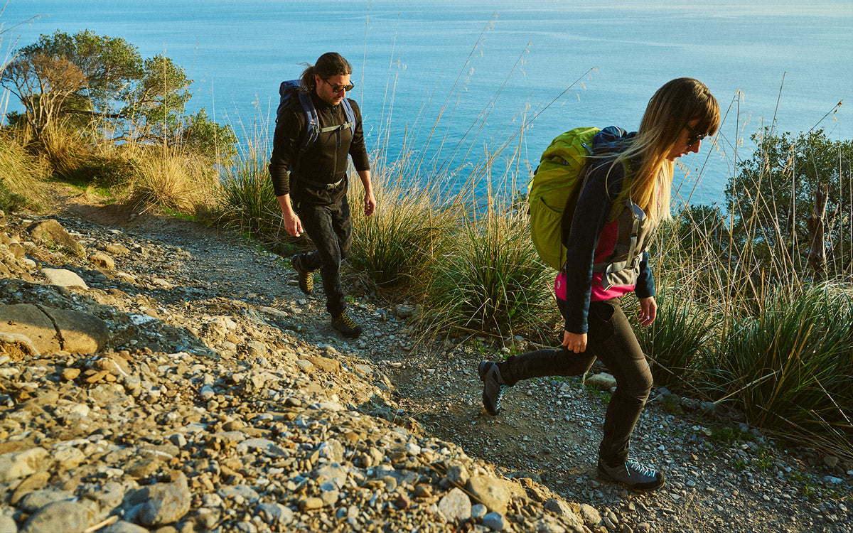 2 ragazzi durante un'escursione di trekking vista mare, attrezzati con abbigliamento e accessori Scarpa