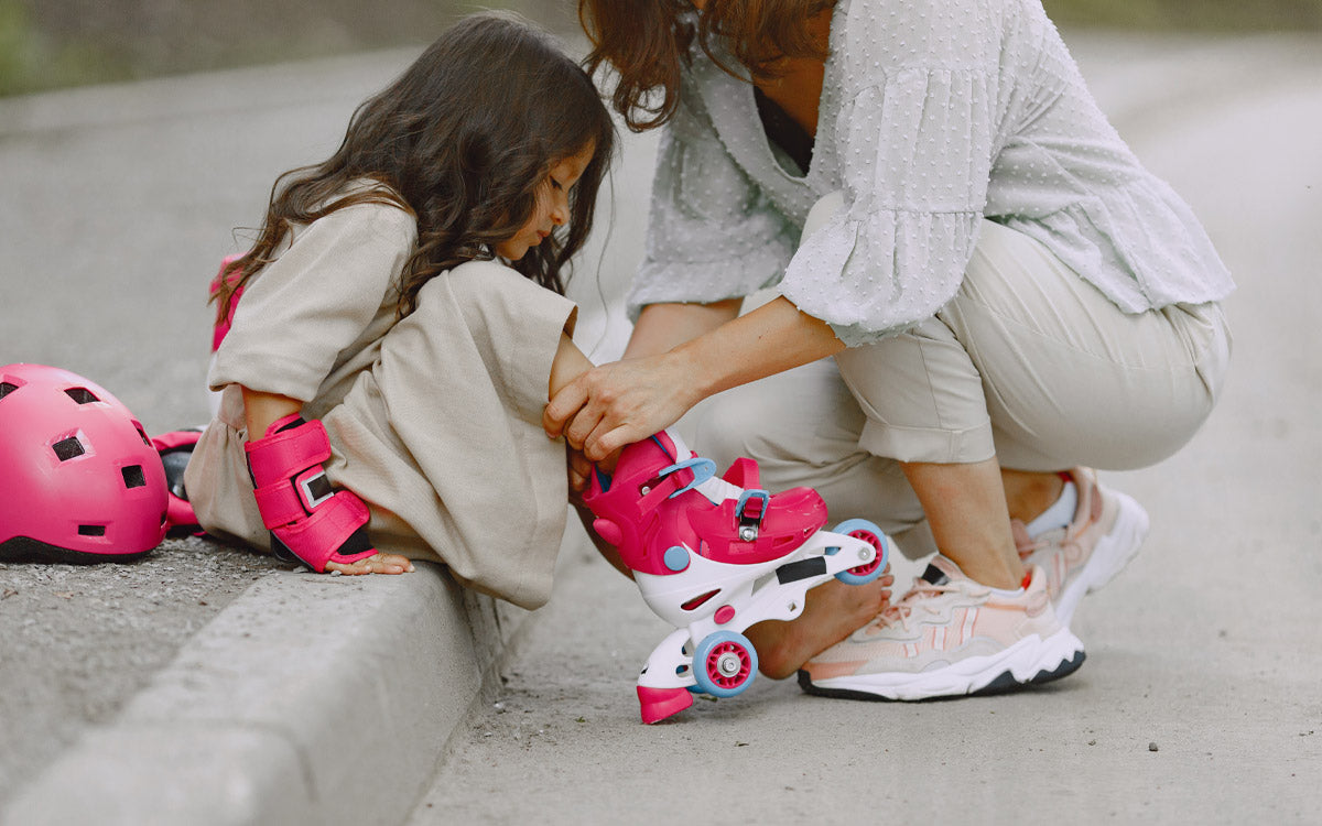 Una mamma aiuta la figlia a mettere i pattini correttamente e tutte le protezioni