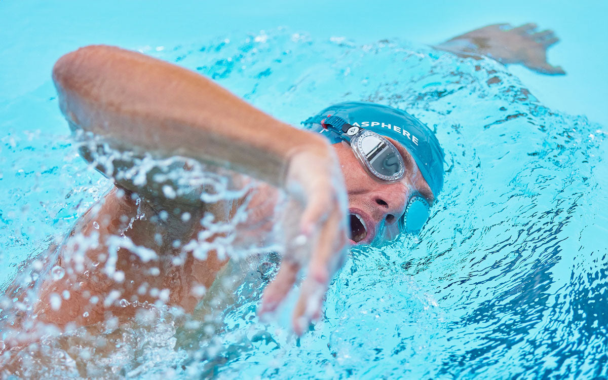 Un ragazzo nuota a stile libero in piscina con occhialini Aquasphere
