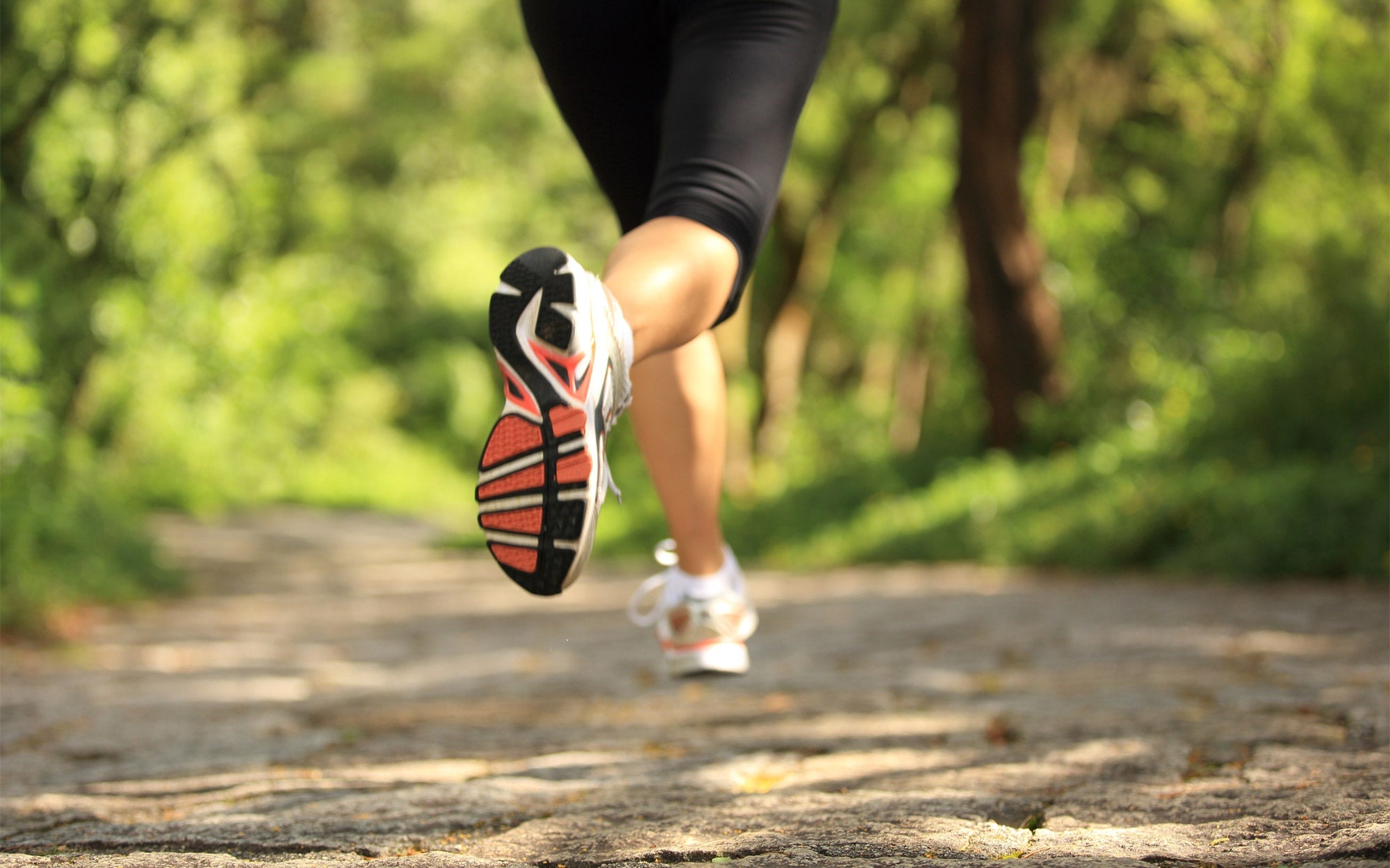 Fotografia di una ragazza mentre corre, inquadrata dal basso con focus su gambe e piedi