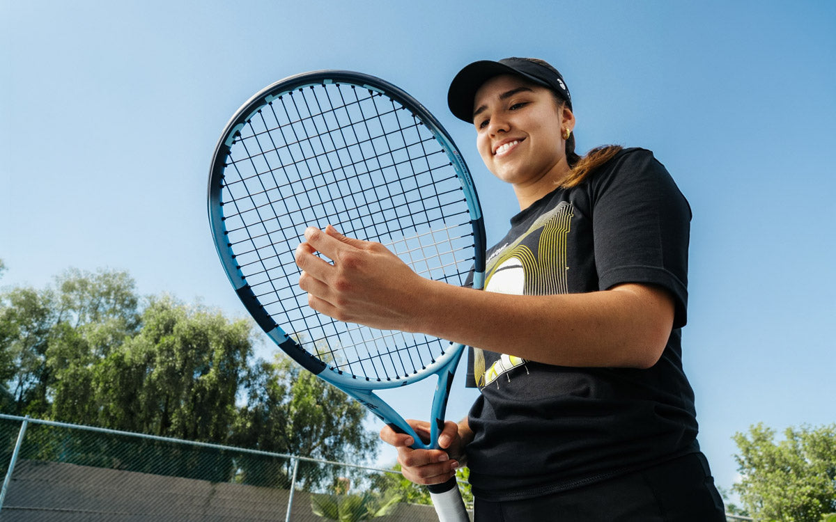 Una ragazza tocca le corde della sua racchetta Babolat
