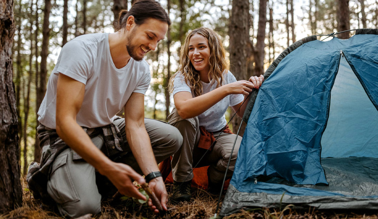 Una coppia monta la tenda nel bosco